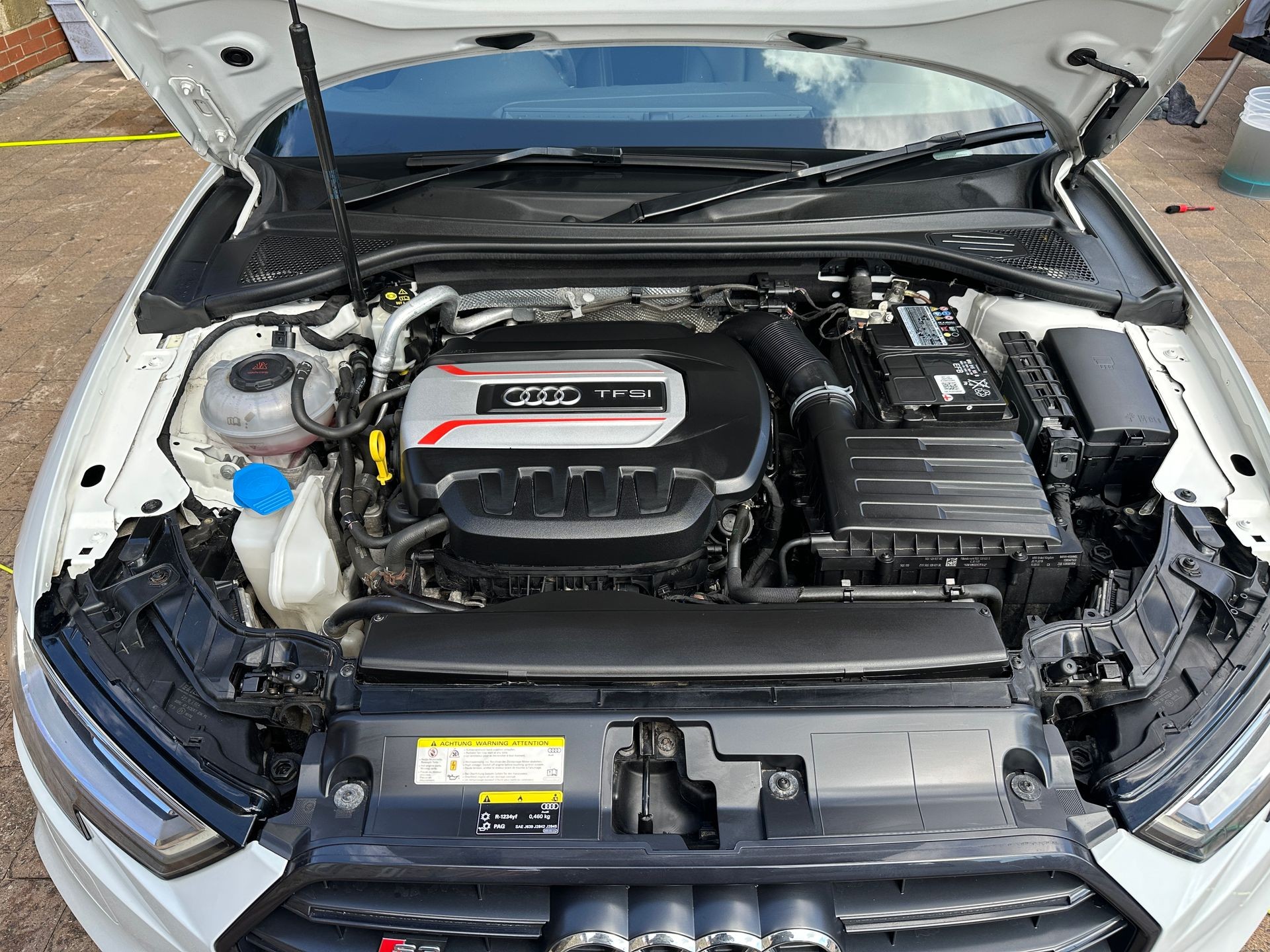 Open car hood showing a TFSI engine and various components of a vehicle's engine bay.